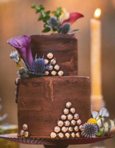 Two-tiered chocolate wedding cake with gold appliques.