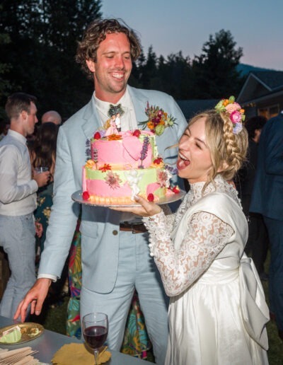 A newlywed couple holding their colourful two-tiered wedding cake at their wedding