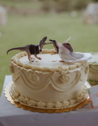 Wedding cake with dinosaur figurines on top.