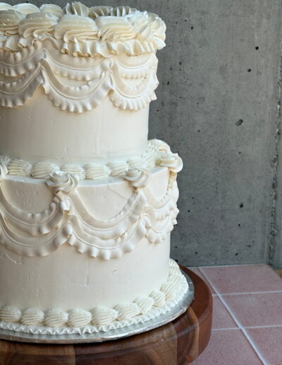 Two-tier white wedding cake with vintage piped buttercream detail